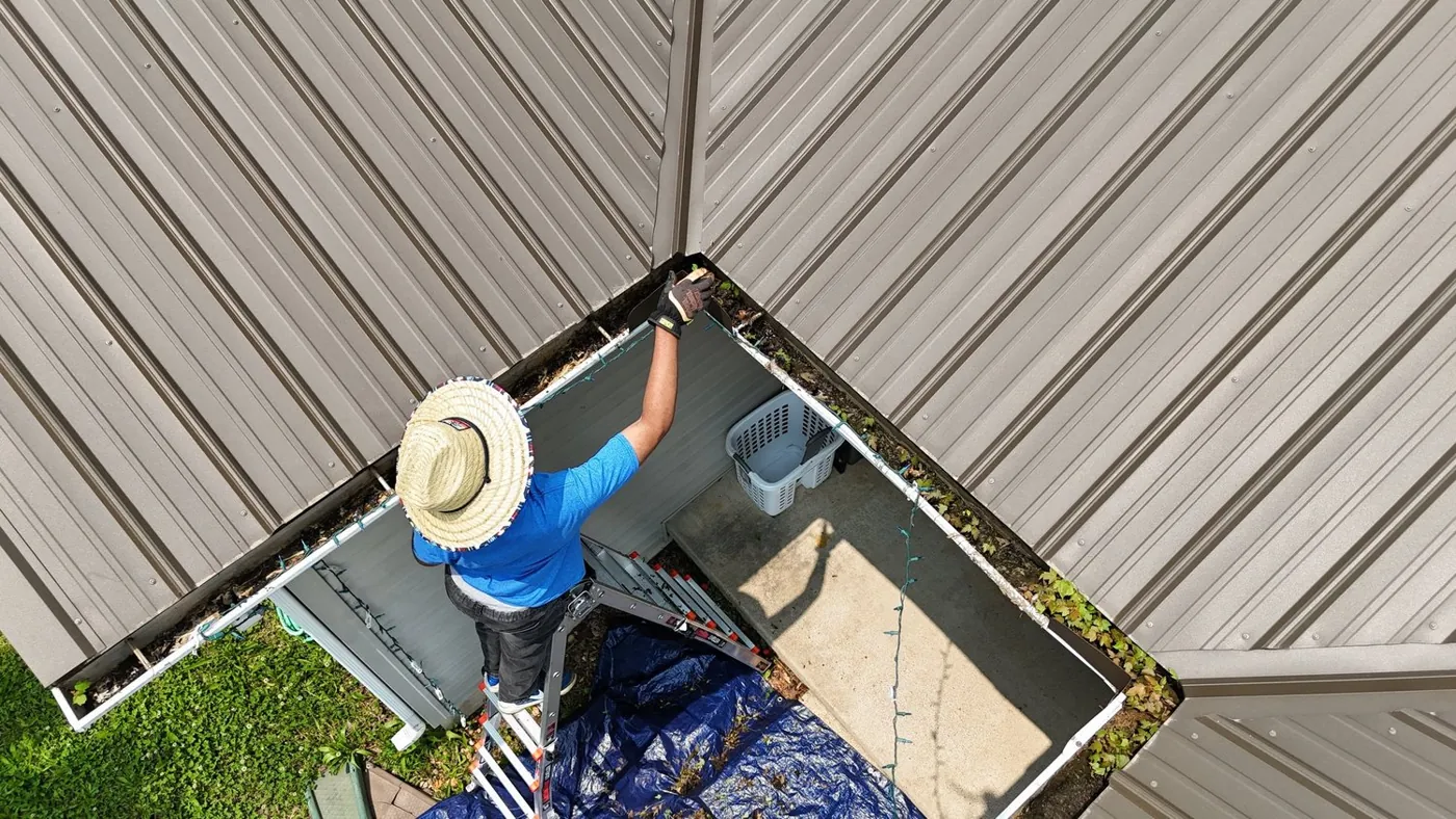 Drone view of a crew member clearing a gutter and roof valley
